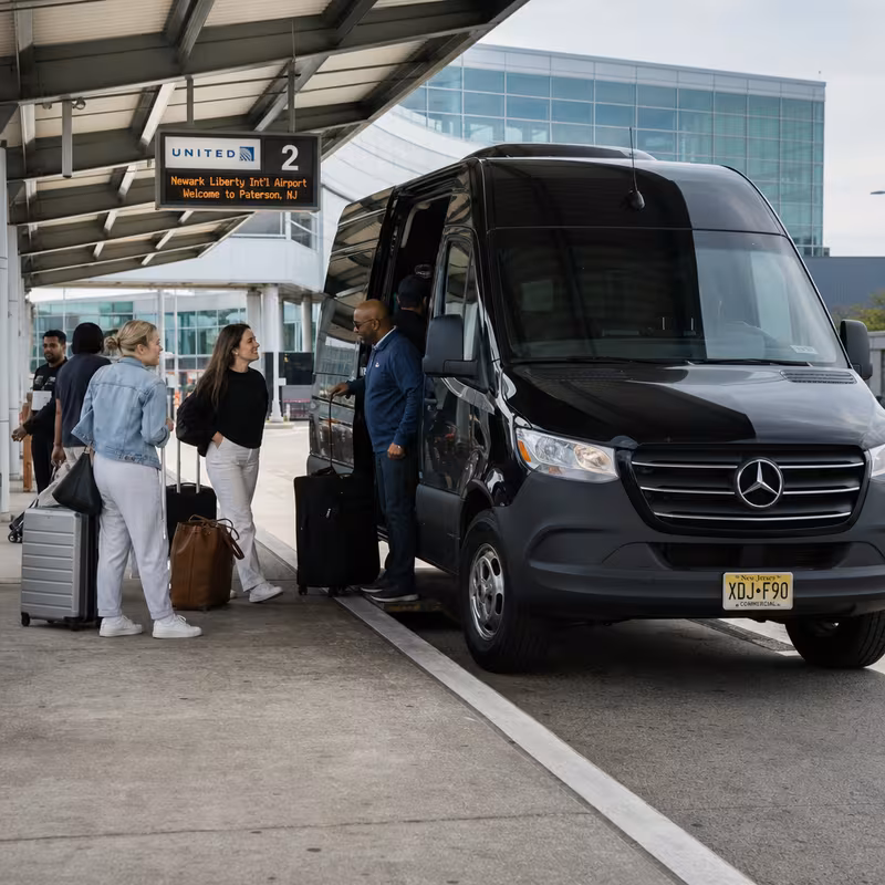 Group boarding a white charter bus for Airport Transportation transportation in Paterson