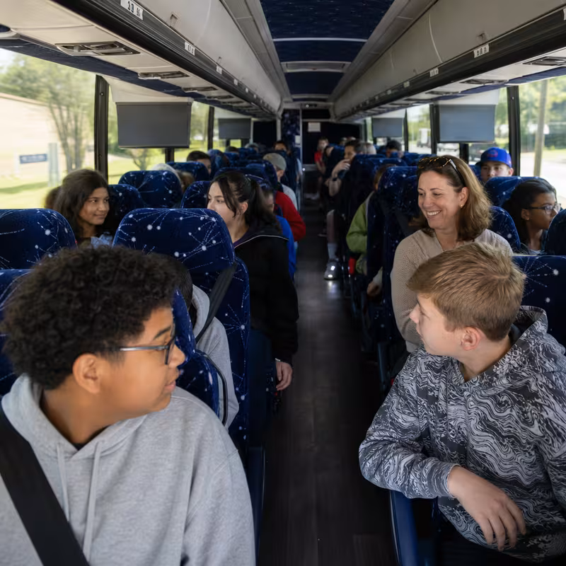 Group boarding a white charter bus for School Transportation transportation in Paterson