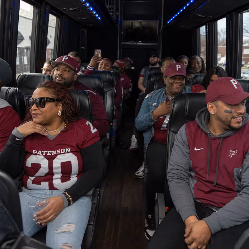 Group boarding a white charter bus for Sporting Event Transportation transportation in Paterson